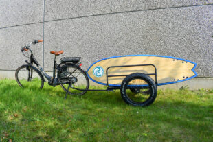 Bicicleta con carrito transportando una tabla de surf